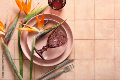 Papier peint  Plates with beautiful strelitzia flowers, glasses and cutlery on beige tile background