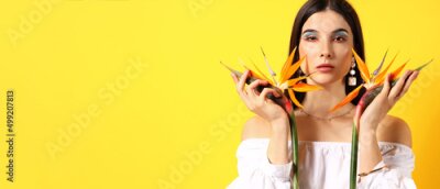 Papier peint  Pretty young woman holding strelitzia flowers on yellow background with space for text