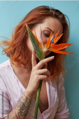 Papier peint  Sexy woman with tattoo holding a strelitzia flower in her hands on a blue background with copy space. Valentine's day card