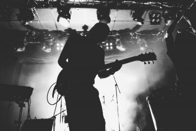 Silhouette de guitariste sur une scène dans une scène brillante s'allume. Noir et blanc