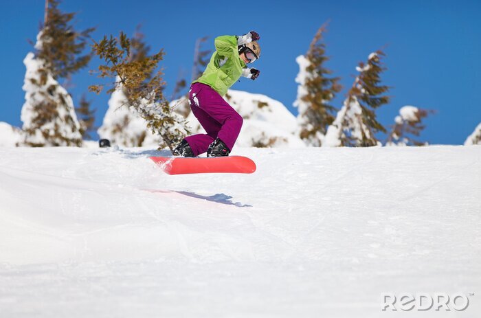 Papier peint  Snowboarder femme sautant sur la pente de la montagne