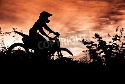 Papier peint  Statut des silhouate saut de motocross sur la lumière ambrée du coucher de soleil fond.