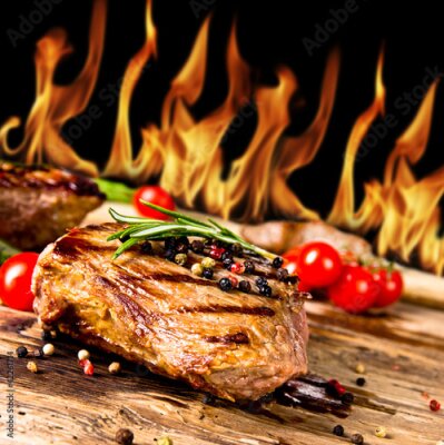 Papier peint  Steaks de bœuf grillé avec des flammes sur le fond