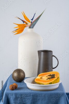 Papier peint  Still life on a blue table: papaya, strelitzia flower

