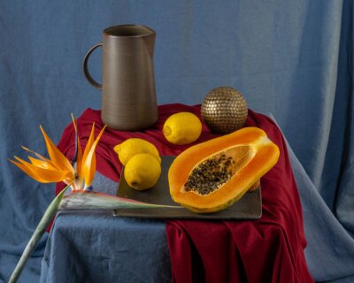 Papier peint  Still life on a blue table: papaya, strelitzia flower

