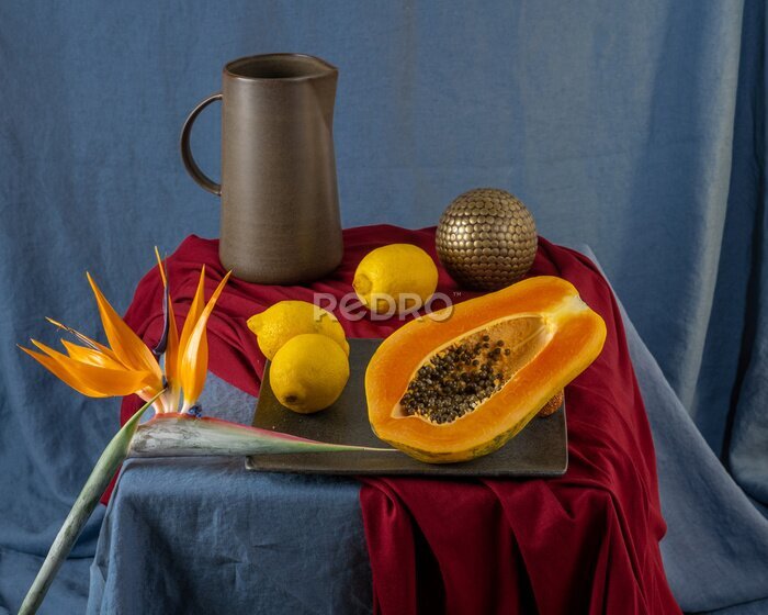 Papier peint  Still life on a blue table: papaya, strelitzia flower
