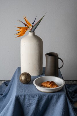 Papier peint  Still life on a gray background: croissant, strelitzia flower
