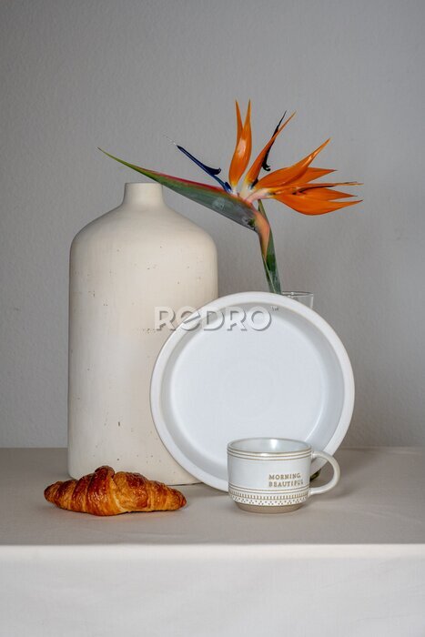 Papier peint  Still life on a gray background: croissant, strelitzia flower
