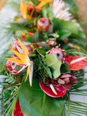 Papier peint  The decor of tropical flowers on the questionnaire table. Red anthurium, palm leaves, red ginger, strelitzia.