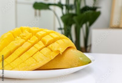 Papier peint  Tropical fresh juicy Mango sliced on a white dish in focus in the foreground, living room out of focus in background featuring Giant White Bird of Paradise tropical house plant (Strelitzia nicolai)