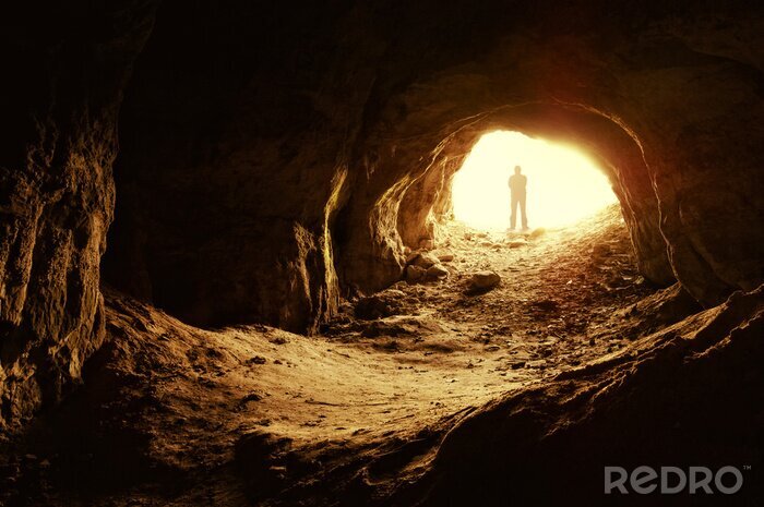 Papier peint  Un homme à l'entrée d'une grotte illuminée
