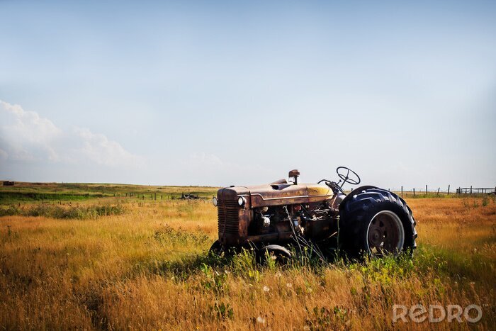 Papier peint  Un vieux tracteur rouillé rouge vintage assis dans un pâturage clôturé dans un paysage de campagne agricole d'été rural
