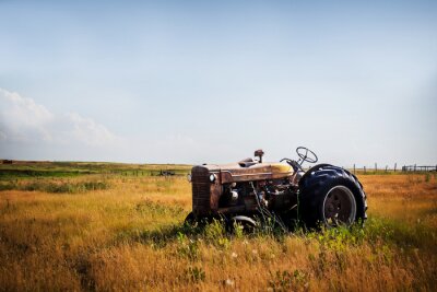 Papier peint  Un vieux tracteur rouillé rouge vintage assis dans un pâturage clôturé dans un paysage de campagne agricole d'été rural