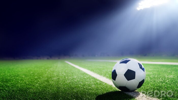 Papier peint  Une balle posée sur le gazon éclairée par un projecteur