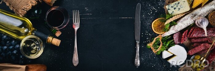 Papier peint  Une bouteille de vin, des fromages et des saucisses traditionnelles sur un fond en bois. Brie, fromage bleu, gorgonzola, fuete, salami. Espace libre pour le texte. Vue de dessus