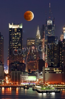 Papier peint  Une lune orange au-dessus des gratte-ciels