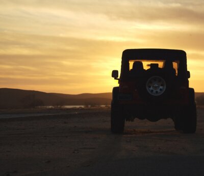 Papier peint  véhicule dans le désert au coucher du soleil