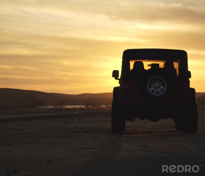 Papier peint  véhicule dans le désert au coucher du soleil