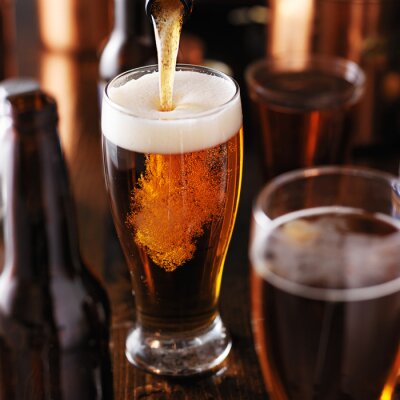 verser de la bière dans le verre sur la table en bois