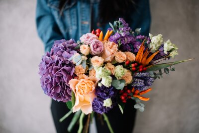 Papier peint  Very nice young woman holding big beautiful blossoming bouquet of fresh hydrangea, roses, campanella peach, eustoma, mattiola, oriental peppers, Strelitzia flowers in peach and purple colors
