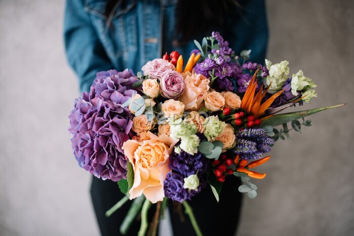 Papier peint  Very nice young woman holding big beautiful blossoming bouquet of fresh hydrangea, roses, campanella peach, eustoma, mattiola, oriental peppers, Strelitzia flowers in peach and purple colors