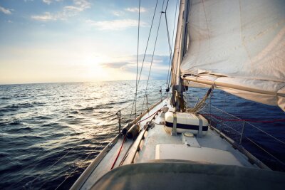 View from the deck to the bow of a sail yacht tilted in a wind on a sunset