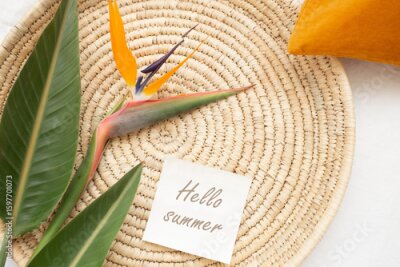 Papier peint  Wicker tray, strelitzia flower and leaves, colored decorative pillows, card with text HELLO SUMMER. Stylish summer home interior decor. Flat lay.