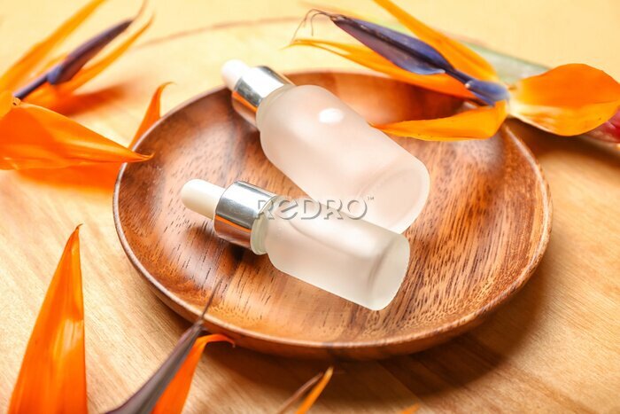 Papier peint  Wooden plate with bottles of essential oil and strelitzia flowers on wooden background