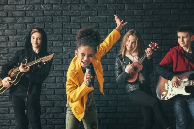 Poster  Band of teenage musicians playing against dark wall