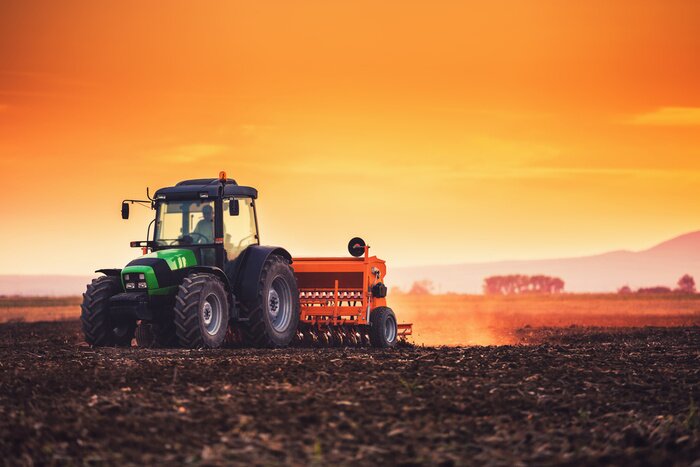 Poster  Beautiful sunset, farmer in tractor preparing land with seedbed cultivator