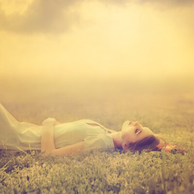 Poster  Belle jeune fille rêve de mentir sur une prairie au printemps magique