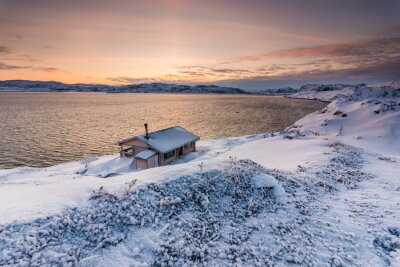 Chalet au bord de l'océan Arctique au coucher du soleil en hiver