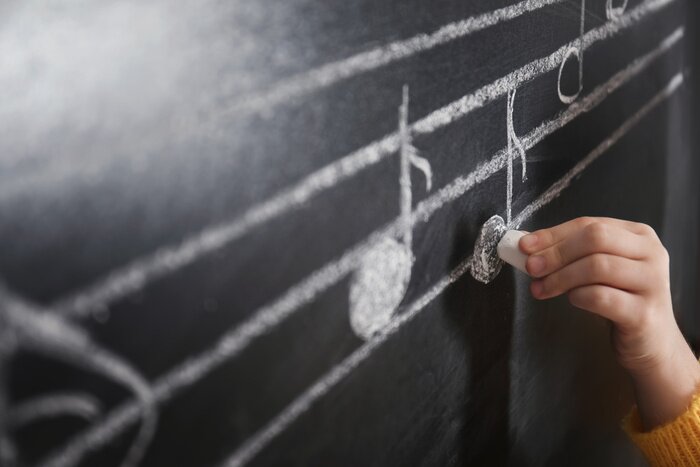Poster  Child writing music notes on blackboard, closeup