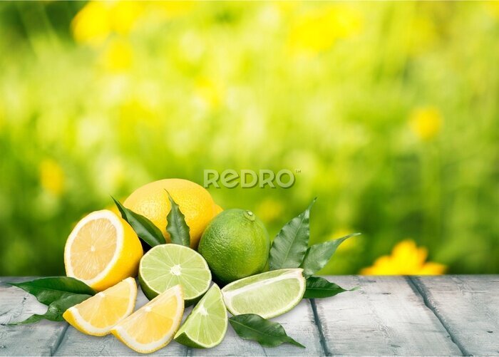Poster  Citrons verts et citrons jaunes étalés sur une table en bois