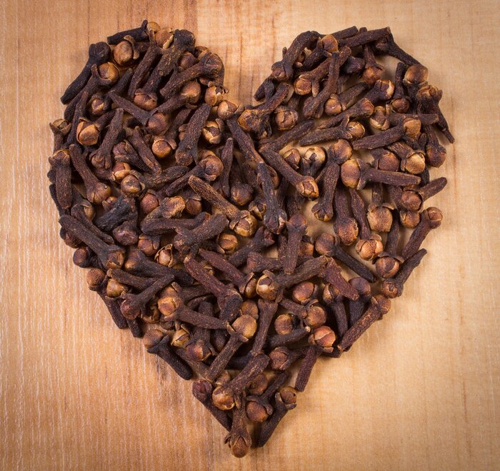 Poster  Coeur de clous de girofle sur table de bois, assaisonnement pour la cuisine
