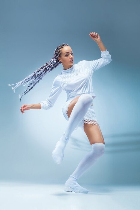 Poster  Danseuse de fille fitness excité attrayant en danse de sportwear isolé sur fond bleu. Concept de mode et de style de vie.