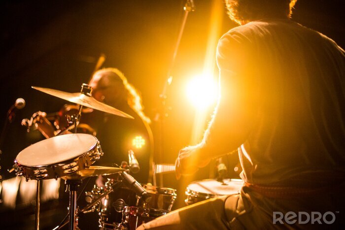 Poster  Drummer on stage playing with a band with gold yellow light shining in background 