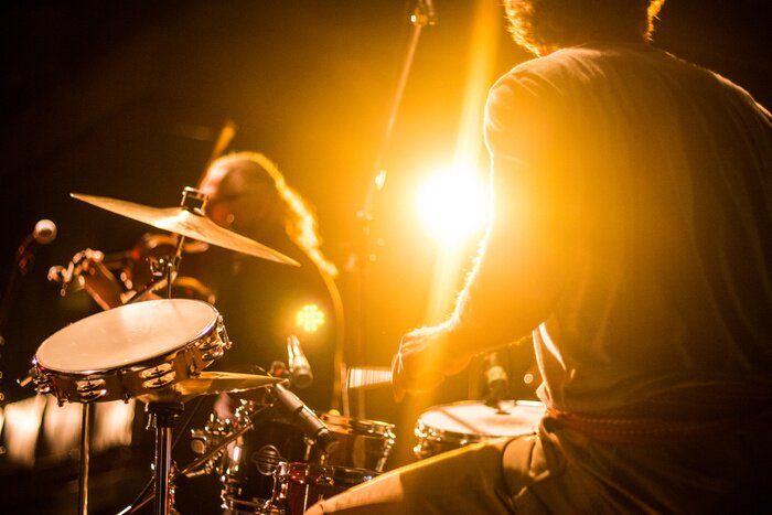 Poster  Drummer on stage playing with a band with gold yellow light shining in background 