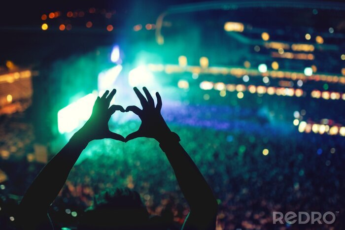 Poster  En forme de coeur mains lors d'un concert, d'aimer l'artiste et le festival. Concert de musique avec des lumières et silhouette d'un homme jouissant de concert