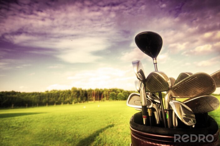 Poster  équipement de golf, clubs au coucher du soleil sur terrain de golf