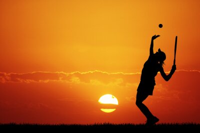 fille jouant au tennis au coucher du soleil