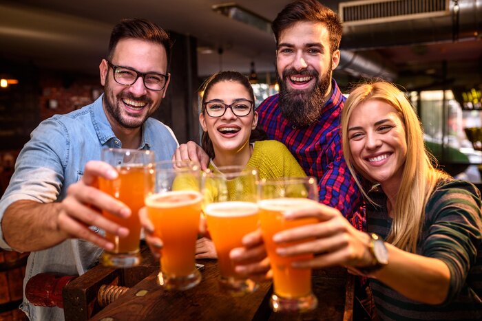 Poster  Group of young friends in bar drinking beer toasting