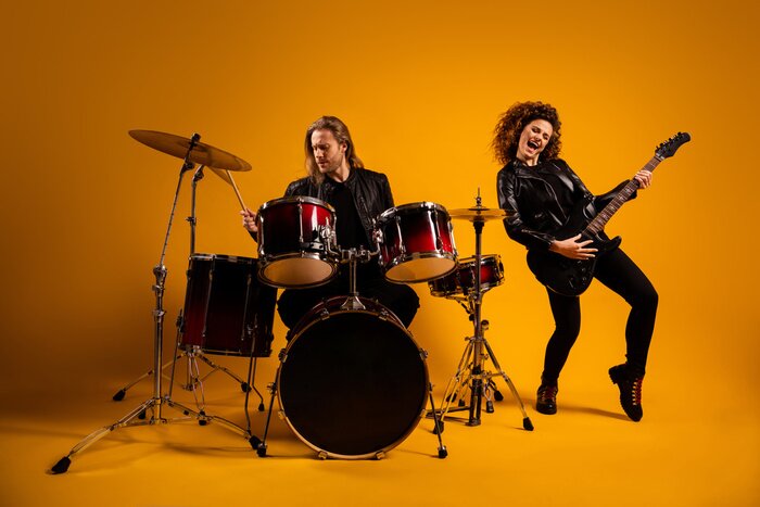 Poster  His he her she nice attractive cheerful cheery glad positive couple playing live music bass sound cymbal having fun hobby isolated on bright vivid shine vibrant yellow color background