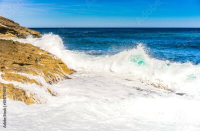Poster  Les vagues de la mer s'écrasent contre la côte rocheuse