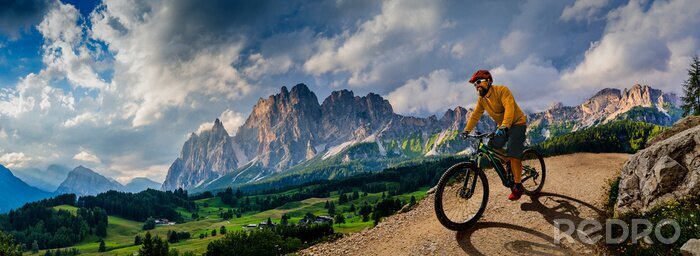 Poster  Man cycling on electric bike, rides mountain trail. Man riding on bike in Dolomites mountains landscape. Cycling e-mtb enduro trail track. Outdoor sport activity.