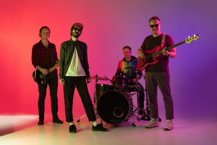 Poster  Motion. Young inspired and expressive music band performing on gradient colored background in neon light. Concept of music, hobby, festival, art. Joyful artist, colorful, bright portrait.