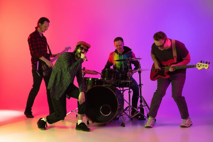 Poster  Motion. Young inspired and expressive music band performing on gradient colored background in neon light. Concept of music, hobby, festival, art. Joyful artist, colorful, bright portrait.