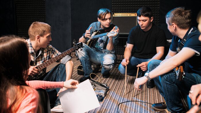 Poster  Musique, bande, discuter, batteurs, fête, chanson. Vue de face sur les jeunes musiciens assis sur le sol, tout le monde regardant le gars avec des pilons.