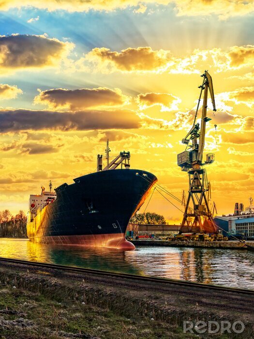 Poster  navire de chargement et le port au coucher du soleil.