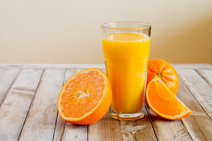 Poster  Orange fruit and glass of juice on white wooden background